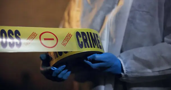 Police, hands and yellow tape for crime scene, investigation and barricade in night for warning, danger or sign. Forensic inspection, person or detective with security for robbery, murder or no entry.