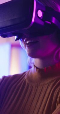 VR, oyun ve kadınlar evde kulaklık, teknoloji ve online yayın tecrübesiyle rahatlar. Sanal gerçeklik, oyun ve kız yaratıcı yazılımı fütüristik esport gözlükleriyle yakından incelerler..