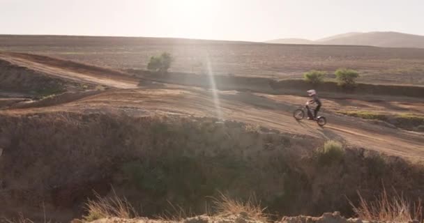 スポーツ オートバイ 砂漠で運転する人 砂の上の道を離れてスタントの挑戦のために丘にジャンプします トレイル ドライバーは 田舎でのスキル テクニック アドベンチャーでバイクで旅行します — ストック動画