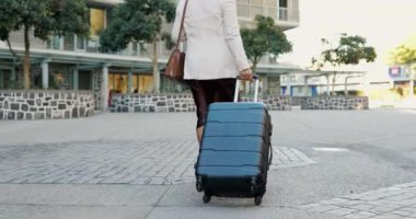 İş kadını, bavul ve seyahat fırsatı, göçmenlik ya da kariyer gezisi için şehre yürümek. Havaalanı, otel ya da konuma yolculuk için bavulu olan profesyonel kişi ya da girişimcinin arkası.