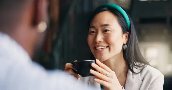 Happy asian woman, friends and coffee at cafe for conversation, catch up or break together. Young female person talking to man with smile or cup of tea for friendly discussion at indoor restaurant.