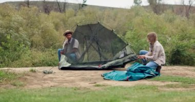 Kamp, çift ve açık havada çadır kurmak tatilde, tatilde ve ırklar arası insanlar doğada seyahat eder. Kamp yeri, erkek ve kadın birlikte kurulacak, kırsal alanda macera için hazırlık ve yardım.