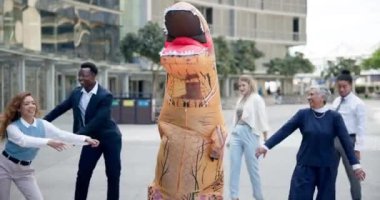 İş dünyası, insanlar ve ofiste mutluluk içinde eğlenceli şişme dinozor kostümü içinde dans etmek. Komik, grup ve çılgın takım iş yerinde diş ipi hareketinde komedi karakteri oluşturuyorlar..