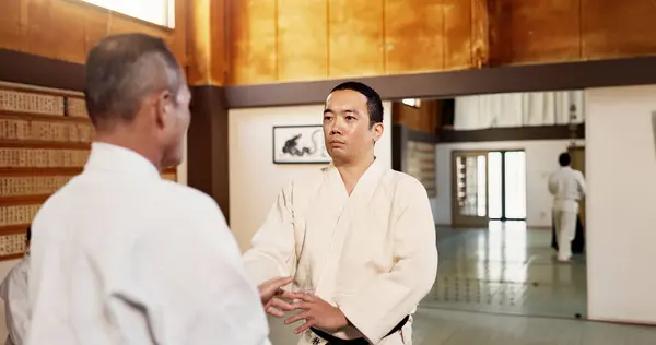 Aikido dojo, men and sensei for martial arts, learning or advice for combat at training, gym and class. Japanese people, moving hands or sport for fight, workout or fitness with zen, conflict or club.