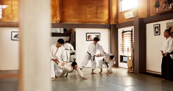 Aikido dojo, students and fight for martial arts, strike or together for combat at training, gym or class. Japanese people, group and sport for exercise, workout or fitness with zen, conflict or club.