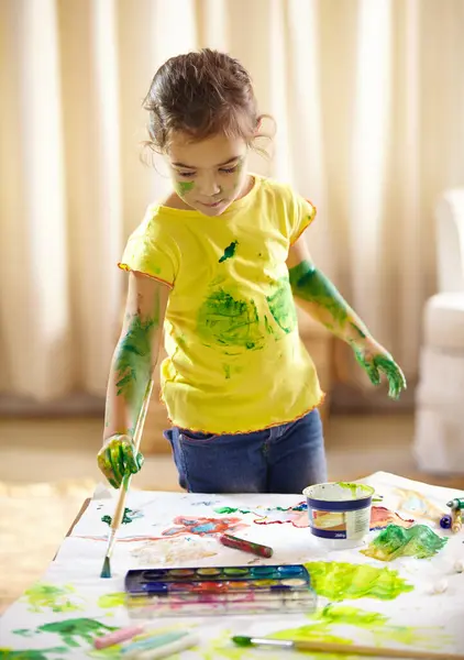 Painting, messy and girl kid with homework, assignment or project for school at home. Colorful, art and young student drawing on paper for creative hobby, child development or activity at house