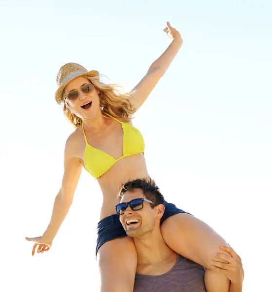 Man, smiling and woman excited on shoulders for summer break, vacation or holiday together. Couple, happy and in love travelling for romantic trip, relaxed beach date and bonding in sunlight.