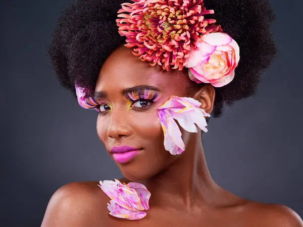Flowers, portrait and salon with afro black woman in studio on dark background for natural cosmetics. Face, beauty or skincare and young model with protea in hair for aesthetic wellness at spa.
