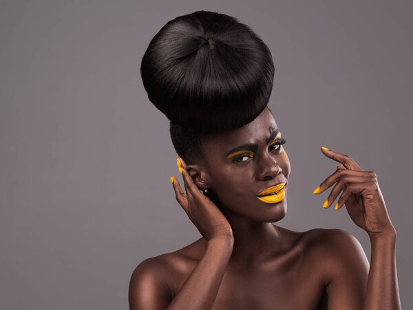 African, model and studio portrait with makeup, beauty and creative yellow lipstick. Bold, woman and skin with confidence, dramatic hair and bun for glamour and trendy cosmetics on grey background.