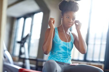 Kadın, kulaklık ve egzersiz için spor salonunda sağlıklı vücut, dayanıklılık ve sağlıklı egzersiz. Sağlık, dinleme ve kürek çekme makinesi tesisindeki sporcunun eğitim, canlı müzik ve yüzü.