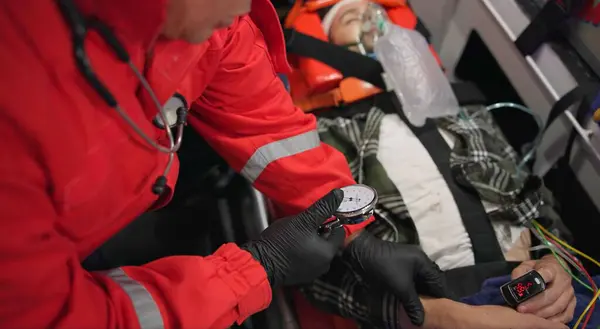 Watch, pulse and hands of a paramedic with a patient in an ambulance for rescue during an emergency or accident. Heartbeat, time and service with an emt closeup in a vehicle to save a man from above.