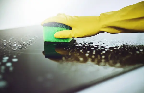 Surface, cleaning or hands of person with sponge or gloves in kitchen in home for healthy hygiene. Removal, oven and cleaner with soap to scrub, wipe or disinfect stove of mess, bacteria or germs.