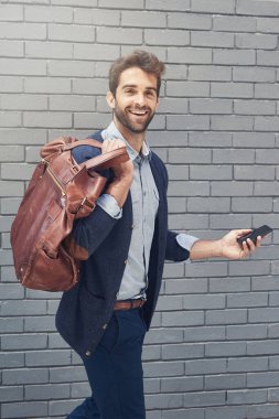 Açık hava, portre ve adamla iş, akıllı telefon ve çalışanla daktilo ve duvar arkası olan çanta. Moda ve dijital uygulamalı cep telefonu ve mobil kullanıcısı olan New York şehri..