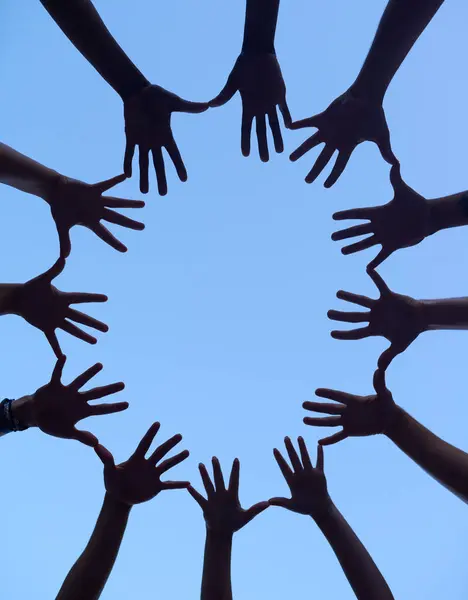 Hands, group and silhouette for support huddle, low angle of collaboration for team building and people outdoor. Partnership, solidarity and community together on sky background, synergy and trust.