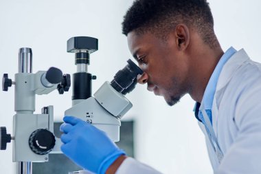Analiz, araştırma ve laboratuarda tıbbi mühendislik için mikroskop kullanan siyah bir adam. Biyoteknoloji, laboratuvar teknisyeni ya da bilim adamı aşı örneğini kontrol ediyor.