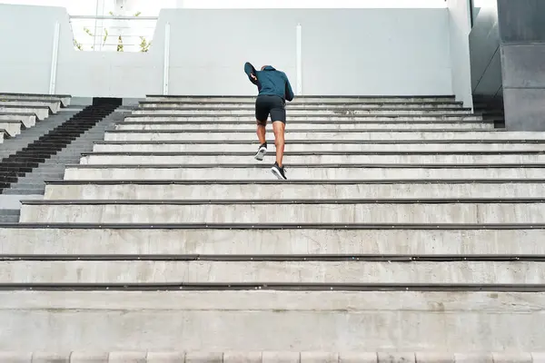 Running, steps and fitness man at stadium for energy, workout or resilience, training and challenge. Arena, stairs and back of runner with sports, performance or cardio exercise for marathon practice.