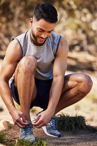 Man, runner and tie shoes in nature, prepare and ready for exercise or outdoor fitness. Male person, athlete and sneakers for jog or marathon training, trainers and footwear for sports or wellness.
