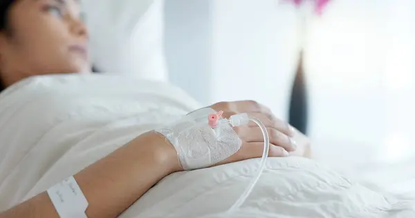 Woman hand, bed and drip in closeup, clinic and thinking with hydration, liquid or supplement. Person, healthcare and wake up with blood transfusion, anesthesia or pharma drugs for pain in hospital.