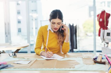 Moda, müşteri ve kadın iş, lojistik ve yaratıcı proje için telefon görüşmesi. Atölyedeki çalışanla fatura, bilgi veya sohbet için terzi, eskiz ve irtibat deposu.