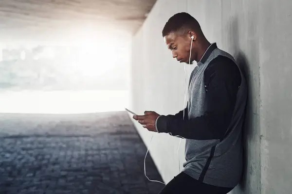 African man, phone and earphones with text, start and workout for training and health. Athlete, music and cellphone for cardio, sports and wellness with exercise and outdoor summer fitness for runner.