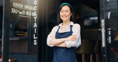 Mutlu Asyalı kadın, kafe ve küçük işletmelerin sahibi. Yönetime güvenerek. Profesyonel bir restoran ya da kafeterya tarafından kolları bağlanmış genç bir kadın ya da garson kızın portresi..