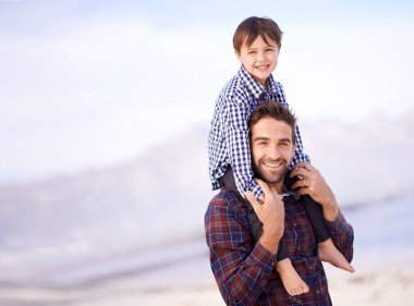 Sahil, portre ve omuzlarında çocuk olan bir adam, açık hava macerasında gülümseme ve maket alanı. Okyanus tatilinde baba ve oğulun eğlence, kaynaşma ve mutlu bir güven için birlikte doğadaki yüzü..