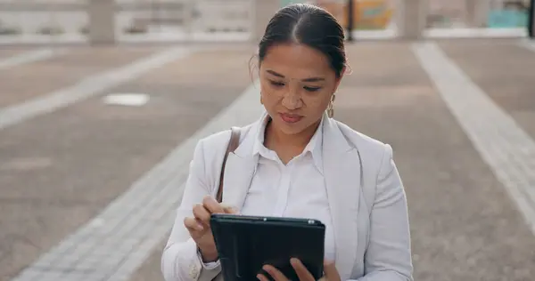 Asian woman, business and browsing with tablet in city for research, social media or outdoor networking. Female person or employee with smile on technology for online search, web or internet in town.