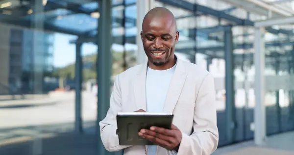 Black man, tablet and typing in city, commute and online, digital and technology. Working, cape town and busy in urban area, office buildings and businessman for networking and checking email.