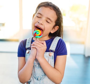 Şeker, lolipop ve tatlı için evde şekerli çocuk, yemek ve gözleri kapalı şeker yemek. Tatlı kız, çocuk ve yalama emici, sağlıksız gökkuşağı renginde abur cubur.