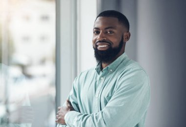 Portre, çalışan ve siyah adam kollarını kavuşturmuş, pencere ve kurumsal hedeflerle profesyonel ve girişken. Face, Afrikalı ve kariyeri hırslı ve gururlu bir danışman..