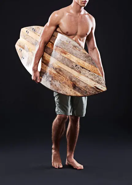 Male surfer and sports with vintage board for exercise and fun in studio portrait. Wave rider and shirtless man with retro surfboard for fitness, workout and summer vacation on black background.