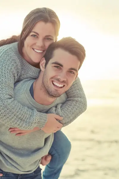 Piggyback, happy and portrait of couple by beach for romantic vacation, travel or holiday together. Smile, love and young man and woman with fun for bonding by ocean or sea on tropical weekend trip