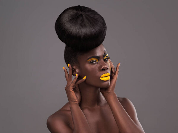 Makeup and portrait of black woman in studio with lipstick, cosmetics and eyeshadow on gray background. Beauty, aesthetic and female model with yellow lip balm, nail polish manicure and glamour.