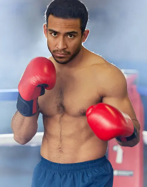 Man, portrait and boxer with gloves in ring for training, workout and practice for fighting competition. Boxing, pro champion and serious with sport for self defense, topless and healthy body in gym.