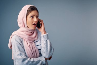 Şaşırdım, telefon ettim ve stüdyoda akıllı telefonlu bir müslüman kadın gördüm. Mavi arka planda şok, vay be ya da omg reaksiyonu vardı. Türban, şaşırmış ve Arap kişi dedikodu, sahte haber ya da gizli için wtf ifade.