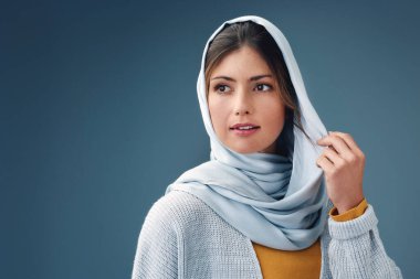 Stüdyoda fikri olan düşünceli, modacı ve müslüman bir kadın mavi arka plan modelleme alanında izole edilmiş. Ciddi, rüya ve İslami kişi vizyon, ilham veya günlük giysiler ile karar tesettüre.
