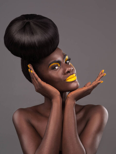 African, model and studio portrait with creative, beauty and cosmetic yellow lipstick. Bold, woman and skin with confidence, dramatic hair and bun for glamour and trendy makeup on grey background.