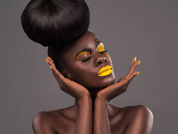 African, woman and studio art with makeup, beauty and creative yellow lipstick. Bold, model and skin with confidence, dramatic hair and bun for glamour or trendy cosmetics on isolated grey background.