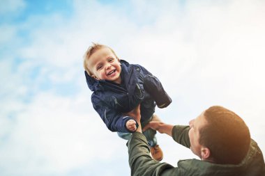 Baba, çocuk ve gökyüzü ile birlikte oynamak, mutlu kahkahalar ve açık hava macerasında kaynaşmak. Baba, oğul ve oyuncu destek oyunları büyüme, gelişme ve eğlence için enerji, gülümseme ve özen ile