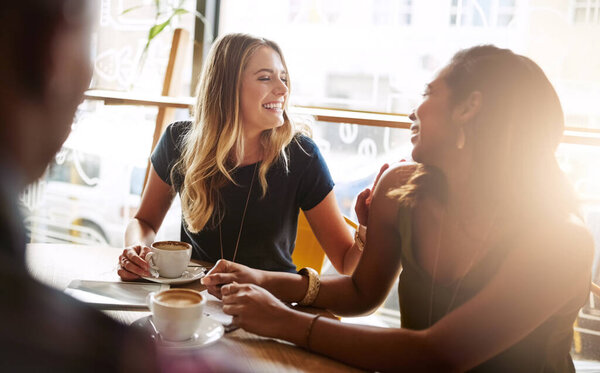 Laughing, friends or women in coffee shop for support, funny conversation or gossip news together. Happy, talking or people speaking of drinking espresso or tea in discussion or chat in cafe diner.