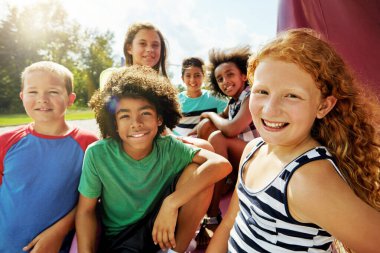 Çocuklar, grup ve portre tatilde arkadaşlarıyla rahatlamak için parkta parkta. Mutlu tatiller ve çocuklar kamp için, oyunlar için ya da ortaokul teneffüslerinde açık havada gülümsemek ya da ara vermek için..