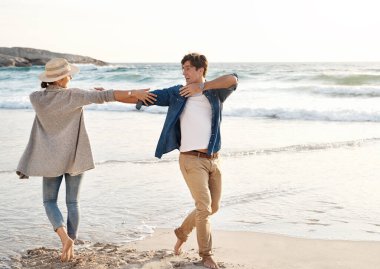 Çift, kumsalda, sahil kenarında ve tatilde birlikte dans edip mutlu mesut yaşayın. İlişki, sevgi ve bağlılık için. Ocean, calm and fun with partner on vacation trip, relax and move for joy on date.