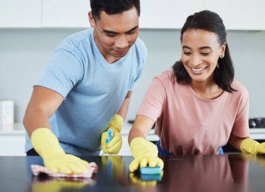 Temizlik, masa ve çift mutfakta birlikte, hijyen, kir temizleme ve bakterilerden korunma için kumaşla birlikte. Mutlu kadın, kimyasallar ve güvenlikle ilgili yardım ettiği için yüzeye çıkan adam..