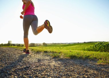 İyi koşu ayakkabıları son derece önemlidir. Toprak yolda koşan genç bir kadın.