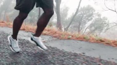 Spor, atlet ve koşmak için yola çıkmış bir adam. Ormanın doğasında maraton koşmak için egzersiz ve antrenman yapıyor. Sabah sağlık, spor ve enerji için ayaklarında ayakkabı olan açık hava, koşucu ve erkek..