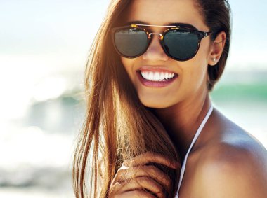 Portrait, beach and woman with sunglasses, vacation and smile with happiness, tropical island and weekend break. Face, person and girl with eyewear, seaside and holiday with getaway trip and sunshine.