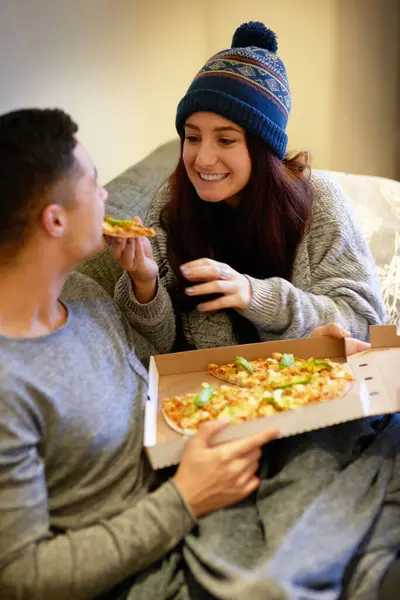 Man, woman and pizza on couch for eating, nutrition and fast food together in apartment with smile. Couple, meal and happiness with love on sofa for dinner, weekend and hungry people in London.