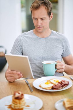 Adamım, tablet ve sabah kahvaltısı ya da evde okumak ya da kahve, yumurta ya da waffle ile beslenme yemeği. Erkek insan, rahatlamak ve internet haberlerini daire mutfağında dinlemek, dinlenmek, yayın yapmak ya da bağlantı kurmak için.