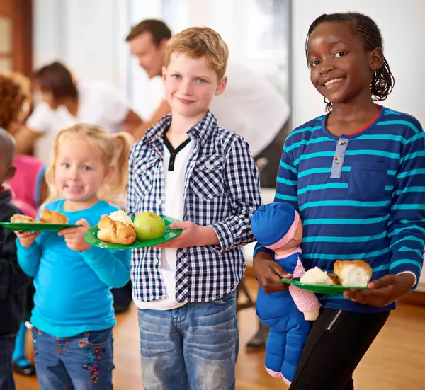 stock image Children, portrait and food poverty or volunteer organization at orphanage for nutrition, helping or non profit. Boy, girls and face or missionary service with meal for community, kids or donation.