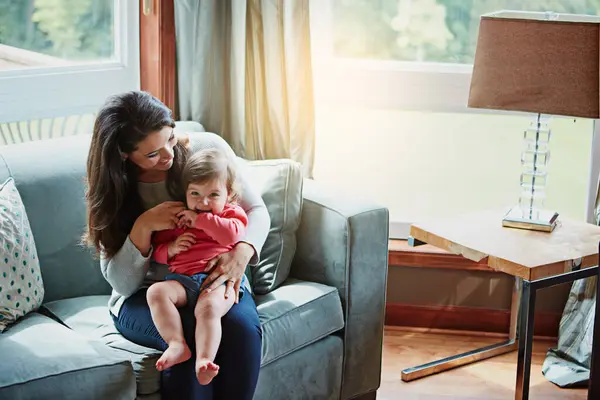 stock image Mother, child and happy on couch in home with relax, bonding and love with embrace for fun together. Family, woman and daughter or kid with smile for trust, care and security in living room of house.